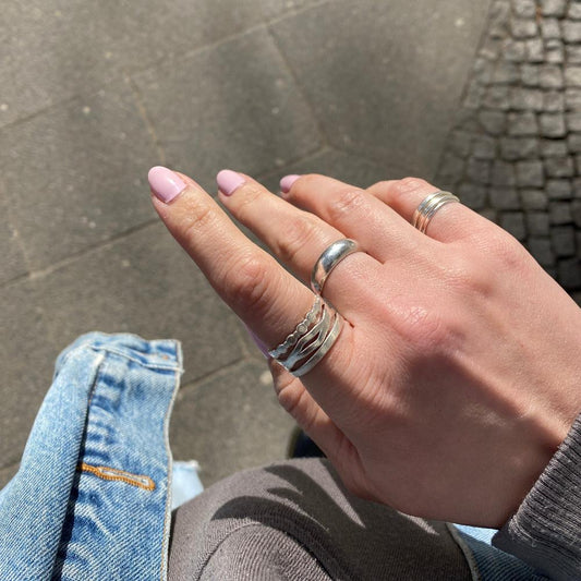 Zu sehen ist eine Hand mit 5 Ringen an den Fingern. Am Zeigefinger sind der Wobble, der Perlenring und der Basic Band gestackt.