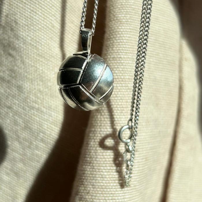 Silberner Volleyballanhänger. Die Nähte des Balls sind in die Halbkugel eingelassen.