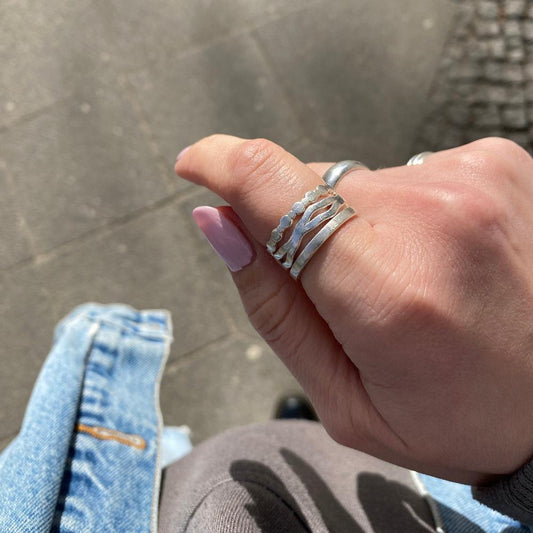 Drei Silberringe übereinander an einem Finger. Der Wobble, der Basic Band und der Perlenring.
