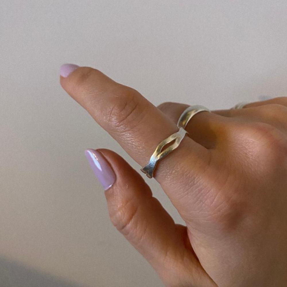 Zu sehen ist ein minimalistischer, leicht organisch geformter Silberring am Finger. Es sind zwei leicht wellige Bänder die ineinander verwoben sind.