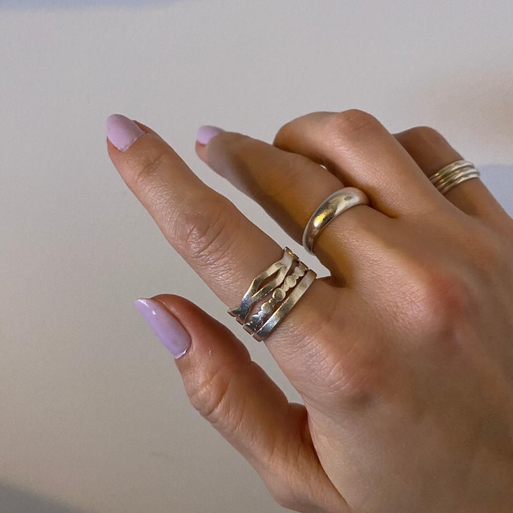 Zu sehen ist eine Hand mit 5 Ringen an den Fingern. Am Zeigefinger sind der Wobble, der Perlenring und der Basic Band gestackt.