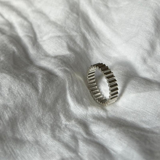 Ein Foto vom Tastsinntraining-Ring "TIA 03.1 Inside&Out Small" auf einem weißen, Leinenuntergrund. Der Ring hat eine zackige Form von außen und innen.