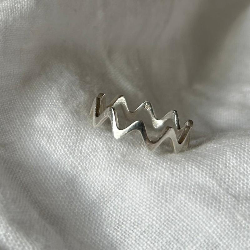Zu sehen ist ein zackiger, minimalistischer Silberring. Die Zacken sind abgerundet, was ihn eher wie einen sehr welligen Ring wirken lässt.
