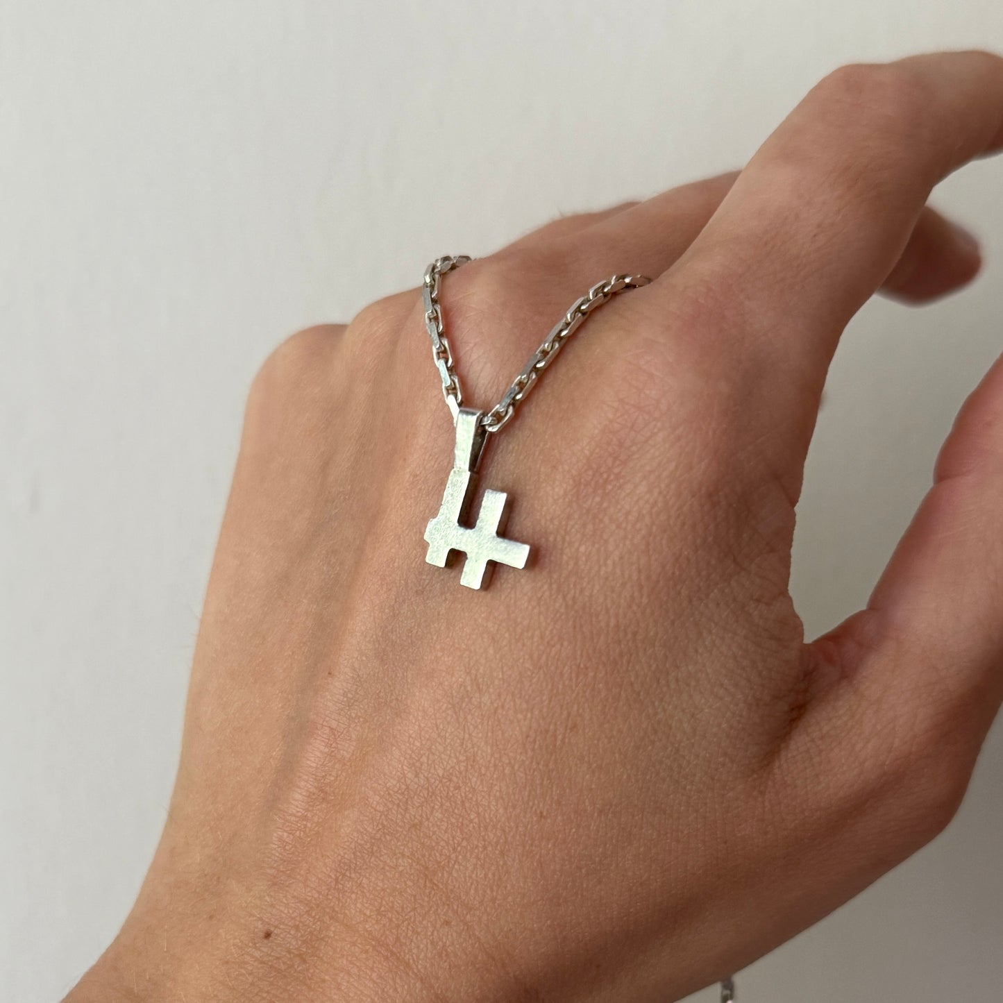 Logo-Kettenanhänger mit Kette an Hand präsentiert.