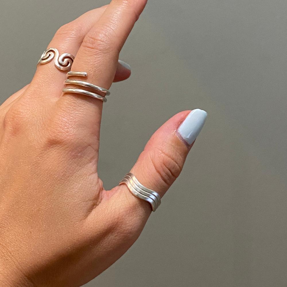 Zu sehen ist eine Hand mit drei Ringen. Der Moneglia Flow, der Olbia Flow und ein Ring, welcher nicht zur Kollektion gehört, sondern individuell angefertig wurde.