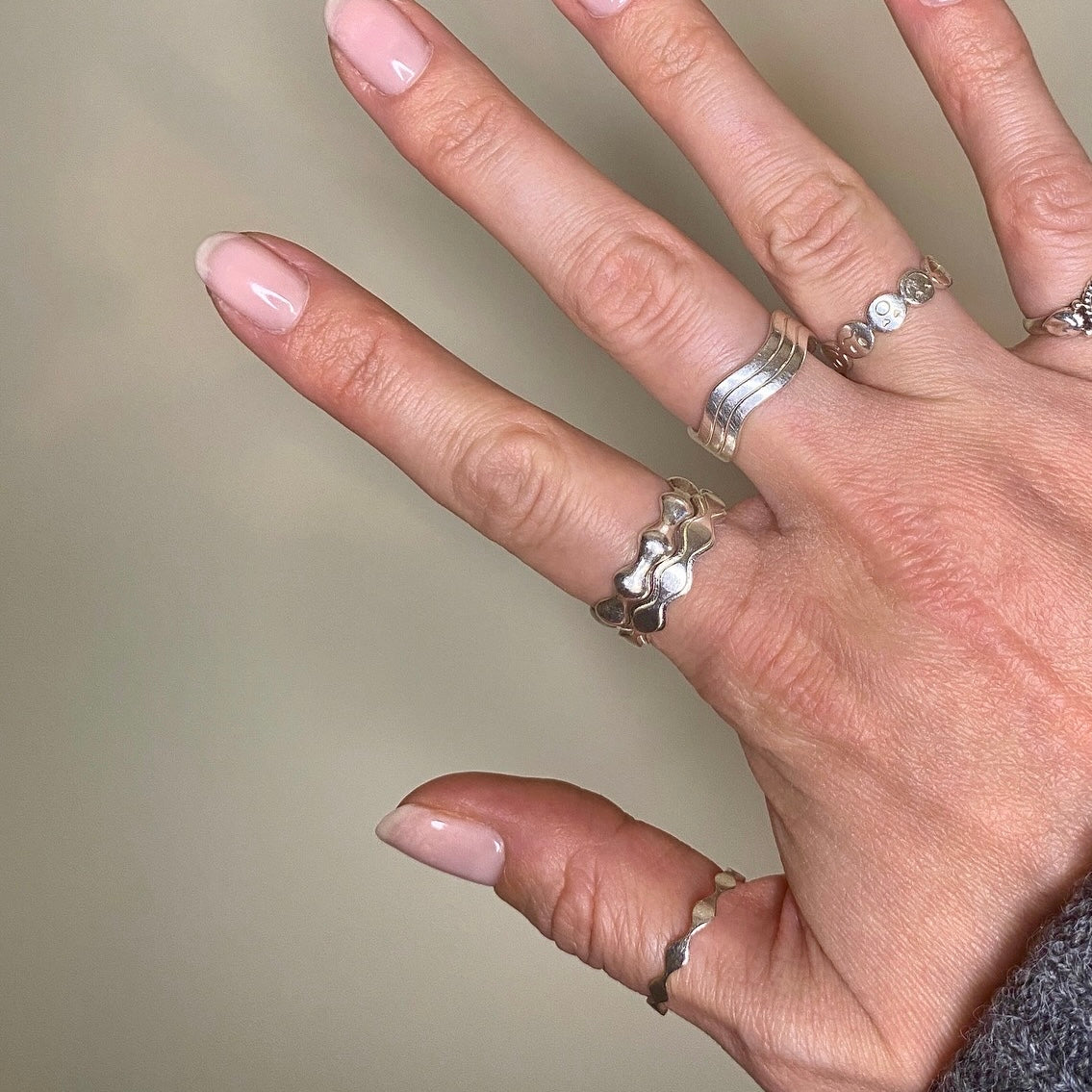 Hand mit Silberringen an jedem Finger